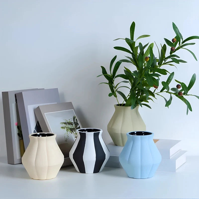 Plusieurs petits vases colorés avec fleurs posés sur une table blanche.