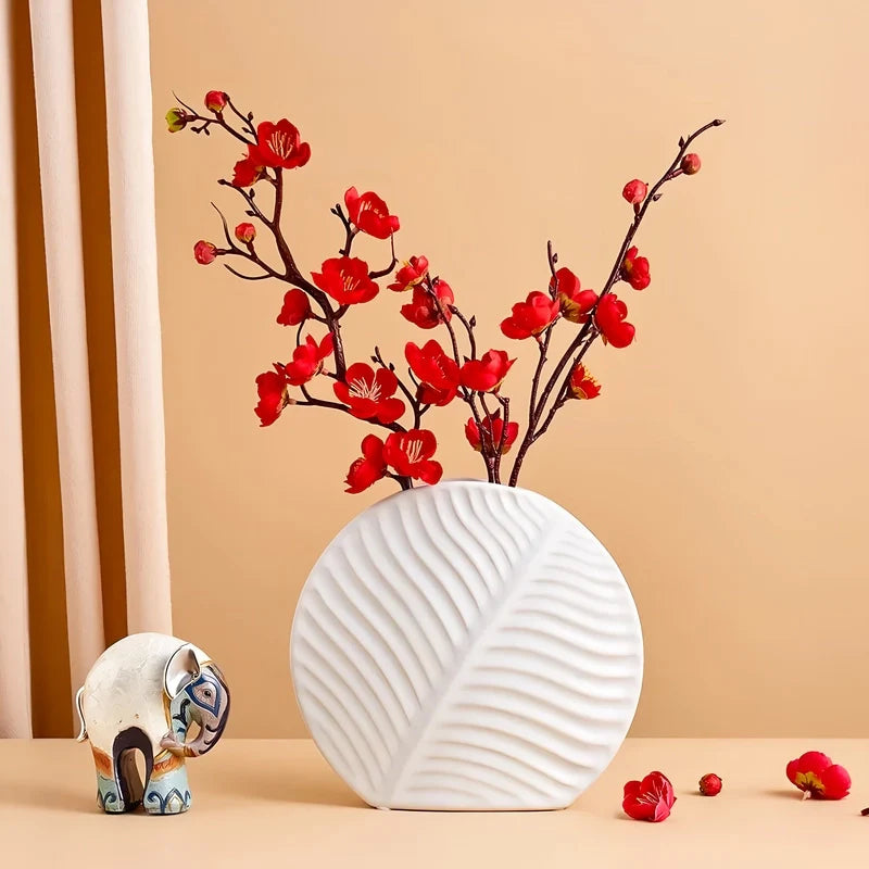 Présentation d'un vase rond blanc original avec fleurs rouges et ornements