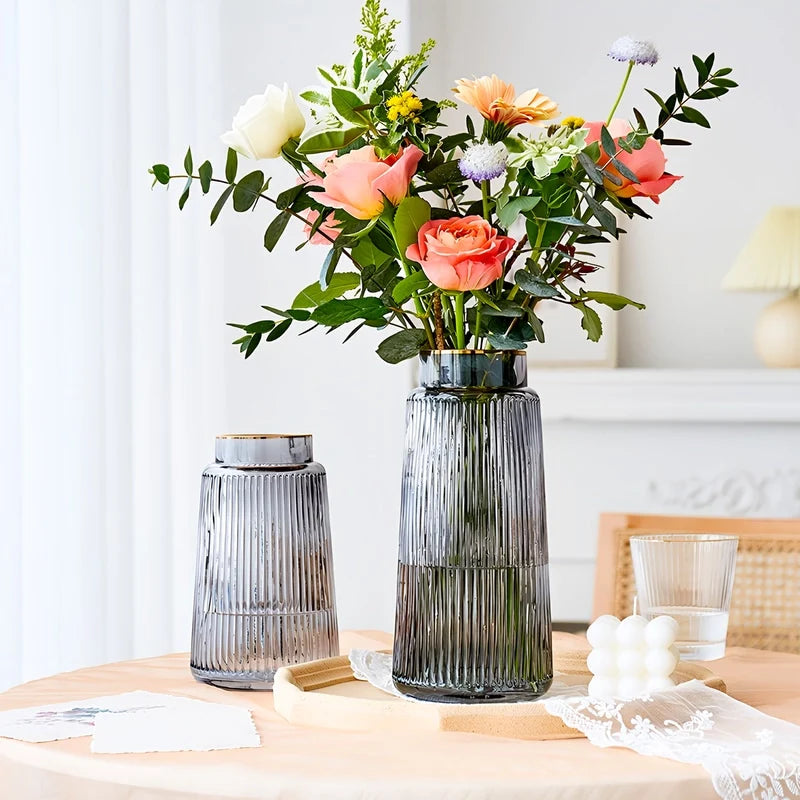 Présentation de deux vases décoratifs gris transparents avec bouquet de fleurs roses