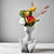 Vase buste femme blanc avec bouquet de fleurs posé sur une table blanche.