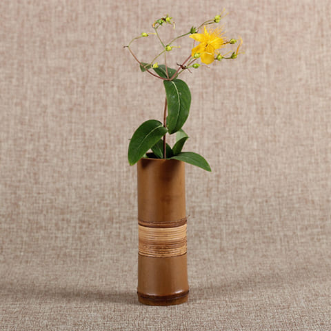 Vase soliflore tubulaire marron en Bambou présentation avec plante et fleur jaune.