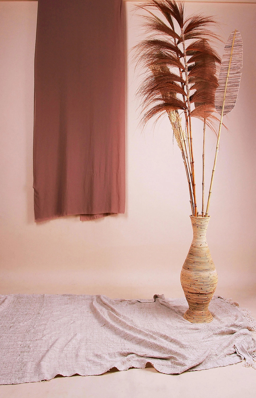 Grand vase à poser au sol en rotin avec fleurs de pampas et feuilles de palmiers