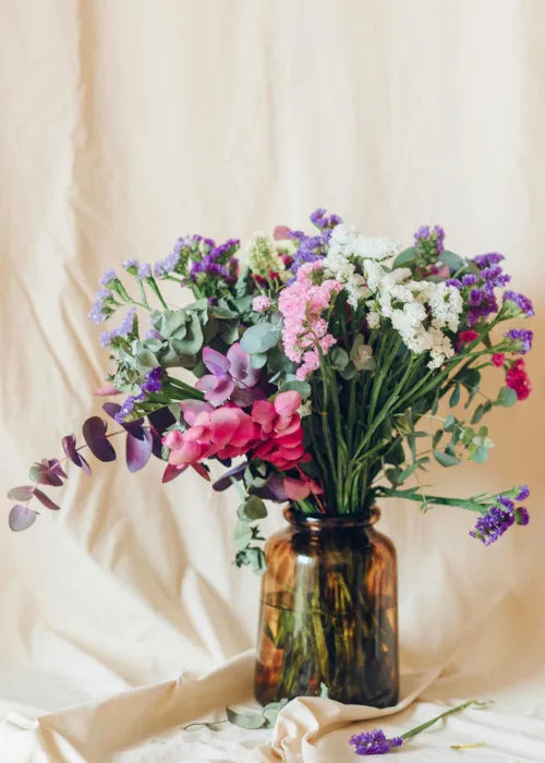 Présentation d'un vase en verre avec bouquet de fleurs printanier.