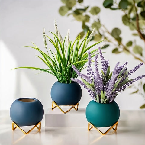 Soliflore boule colorée sur trépied en céramique présentation des modèles bleus avec fleurs et plantes sur une table blanche.