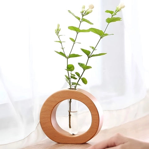 Soliflore Rond en Bois avec Tube en verre et bois présentation avec tige florale sur une table en bois, près d'une fenêtre.
