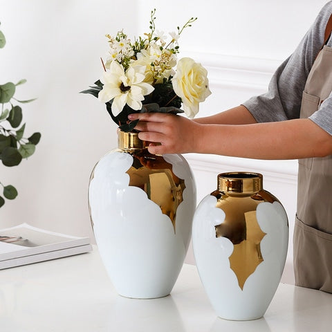 Vase Blanc et Or Motif Feuilles de Houx en céramique présentation des modèles Grand avec bouquet de fleurs et petit sans fleurs sur une table.