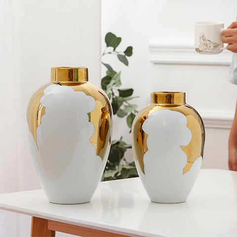 Vase blanc et or motif feuilles de houx présentation des modèles Grand et petit sans fleurs sur une table.