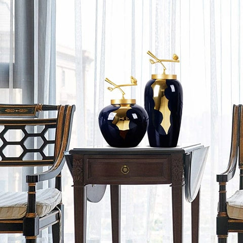 Vase bleu et or luxueux modèles S et M sans fleurs sur une table en bois à volets rabattables.