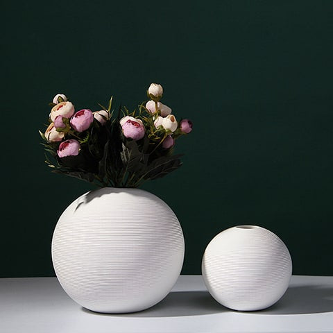 Vase boule blanc minimaliste en céramique présentation des modèles M avec bouquet de fleurs et S sans fleurs sur une table blanche.