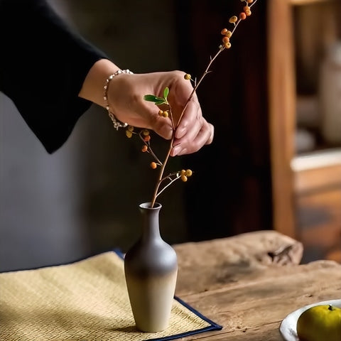Vase Bouteille en Grès Émaillé Bicolore en céramique, mise en scène du modèle B avec une tige sur une table en bois.