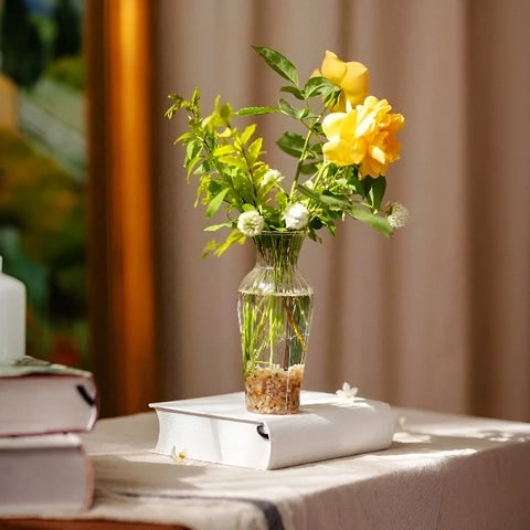 Vase Chaloupé Strié à Collerette en verre présentation avec bouquet de fleurs sur une livre sur une table.