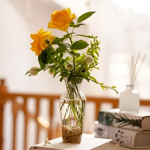 Vase Chaloupé Strié à Collerette en Verre présentation posé sur un livre avec des roses jaunes.