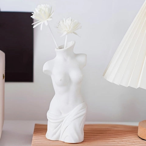 Vase Corps Femme en Céramique présentation avec fleurs blanches sur une table.