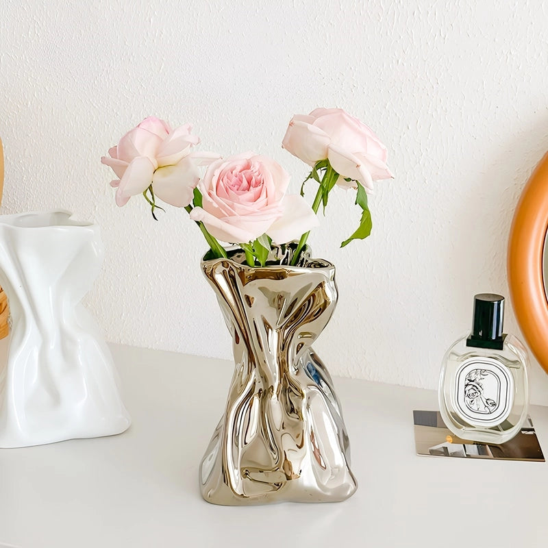 Vase Créatif Froissé Design Original présentation des modèles blanc sans fleurs et argenté avec roses sur une table.