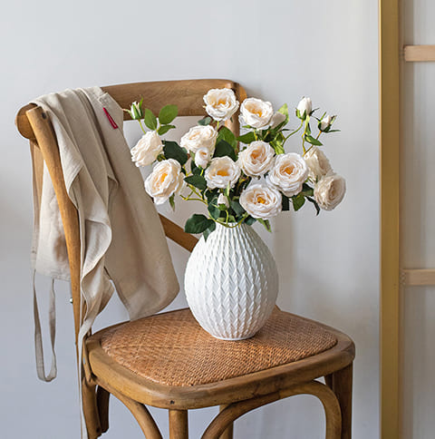 Vase Créatif Moderne à Motifs Blancs présentation du modèle A avec bouquet de fleurs sur une chaise.
