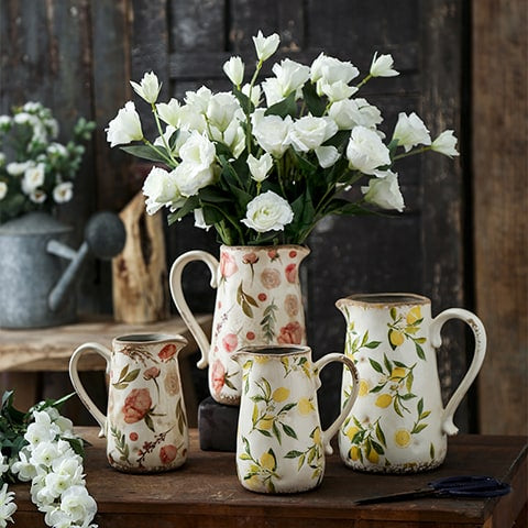 Vase cruche rétro motifs citron ou rose, présentation tous les modèles sur un meuble en bois, modèle grand rose avec bouquet de fleurs blanches.
