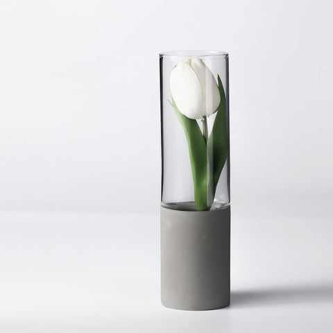 Vase cylindrique bi-matière transparent et gris, en verre et céramique, présentation du modèle B avec une tulipe blanche.