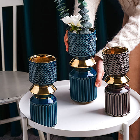 Vase Design Touche Luxueuse Courbe Audacieuse présentation du moèle S bleu sans fleurs ,L bleu avec fleurs et S violet sans fleurs sur une petite table blanche.