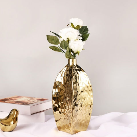 Vase doré relief asymétrique en céramique, présentation du modèles M avec fleurs blanches sur une table.