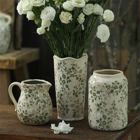 Vase d'époque motif feuillages verts mise en scène des modèles A, D avec fleurs blanches et B sans fleurs sur une table en bois ancien.