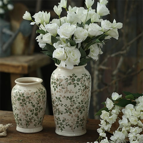 Vase d'Époque Motif Feuillages Verts en céramique présentation des modèles b et d avec bouquet de fleurs blanches sur une table en bois.