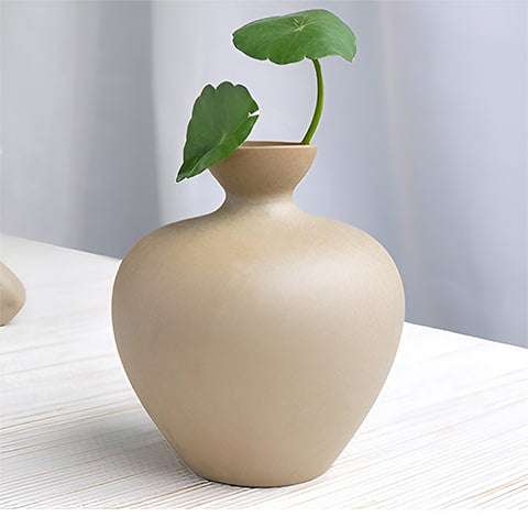 Vase en grès beige en céramique, présentation du modèle A sur une table avec plante verte.