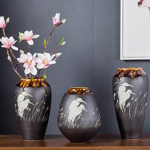 Vase Gris Anthracite Motif Oiseaux Blancs en céramique présentation des modèles S, M avec fleurs et L sur une table en bois, posés côte à côte.