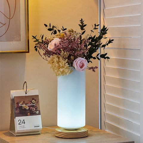 Vase Lampe Romantique pour Fleurs Séchées en verre et bois, présentation du modèle rond avec bouquet de fleurs séchées sur une table de nuit, à côté d'un calendrier.
