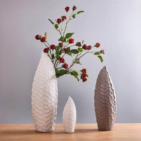 Vase nordique forme de feuille design en céramique présentation de tous les modèles, avec tiges florales rouges dans le modèle L blanc.