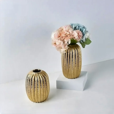 Vase Ovalisé Couleur Dorée en céramique présentation des modèles S sans fleurs et M sur un cube blanc avec bouquet de fleurs.