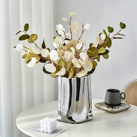 Vase Plissé Élégant Or ou Argent en céramique, présentation du modèle argenté avec bouquet d'eucalyptus sur une table blanche.
