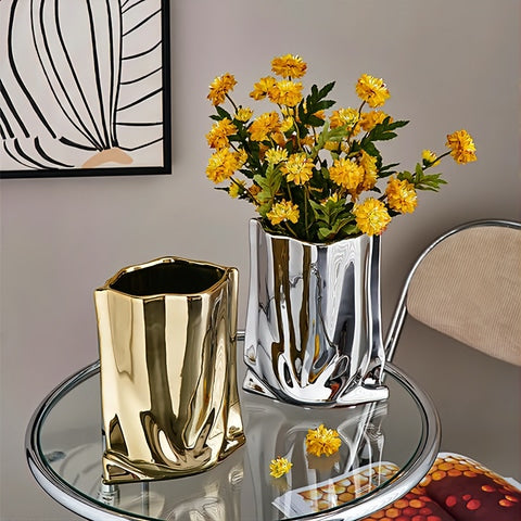 Vase plissé élégant or ou argent en céramique, présentation sur une table en verre des modèles Argenté avec fleurs et Doré sans fleurs.