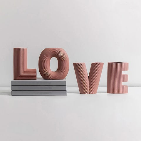 Vase Rayé Art Créatif Lettres Love en céramique présentation modèle rose sans fleurs, lettres L et O sur des livres, V et E à côté sur meuble.