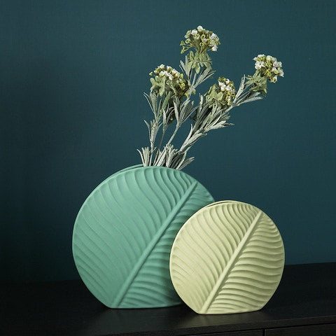 Vase Original Rond Motif Feuille en céramique présentation des modèles vert avec fleurs et kaki sans fleurs sur un meuble.