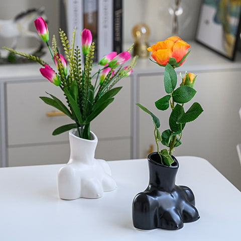 Vase Seins Femme Body Art en céramique présentation des modèles Blanc et noir avec bouquet de fleurs sur une table blanche.