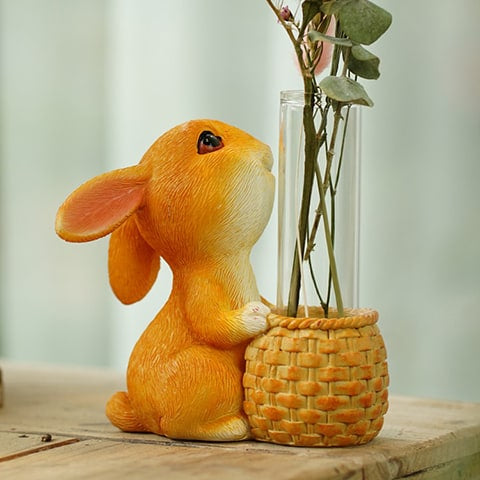 Vase soliflore lapin joyeux en verre, présentation avec plante verte sur une table en bois.