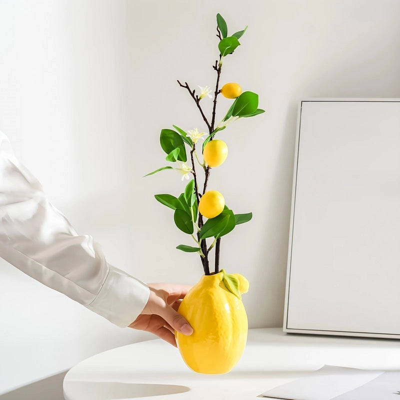 Vase Soliflore Original Forme Citron, présentation tenu en main avec tige artificielle de citron.