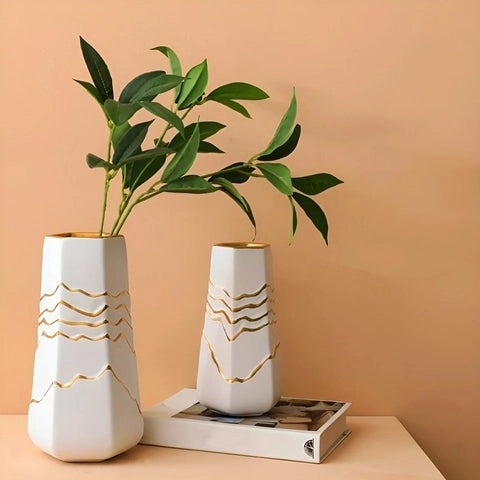 Vase Sophistiqué Polygone Blanc et Doré en céramique présentation et mise en scène des modèles M et S avec feuillage sur une table.