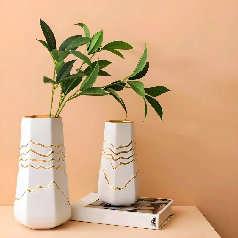 Vase Sophistiqué Polygone Blanc et Doré en céramique présentation et mise en scène des modèles M et S avec feuillage sur une table.