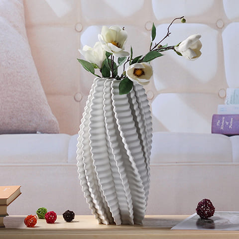Vase torsadé effet 3D modèle blanc S avec fleurs sur une table, mise en scène dans un salon.