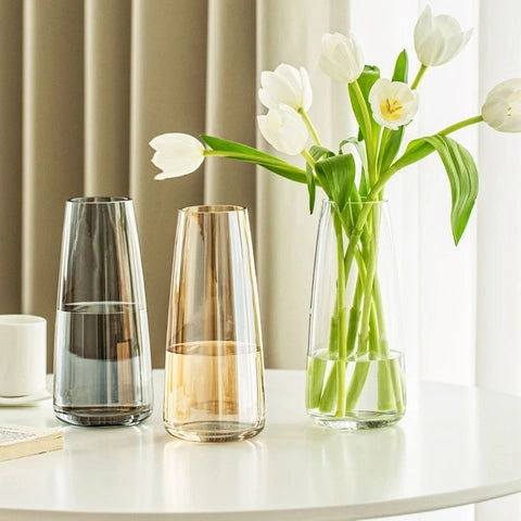 Vase translucide reflet irisé en verre, présentation de tous les modèles avec fleurs blanches posés sur une table blanche.