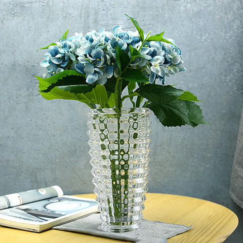Vase Transparent Design Élégant en verre, présentation du modèle petit avec bouquet de fleurs bleues sur une table en bois.