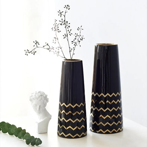 Vase Trapèze Noir Motifs Dorés en céramique, présentation des modèles petit avec fleurs et grand sans fleurs sur une table blanche avec ornements.