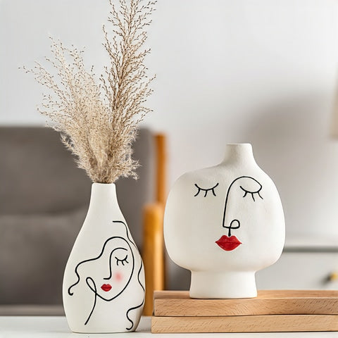 Vase visage femme peint à la main en céramique, présentation des modèles A avec fleurs séchées et D sans fleurs sur une table.
