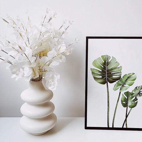 vase blanc design anneaux superposés avec fleurs blanches présentation avec tableau.