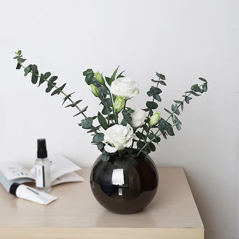Vase sphérique moderne design raffiné présentation modèle Noir avec roses Blanches sur une table.