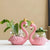 Deux soliflores en résine en forme de flamant rose posés sur une table blanche avec plantes vertes.