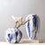 Deux vases bleus et blancs avec fleurs posés sur une table blanche.