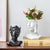 Deux vases femme visage noir et blanc avec bouquet de fleurs posés sur une table en bois.