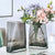 Deux vases gris avec bouquet de fleurs posés sur une table blanche.